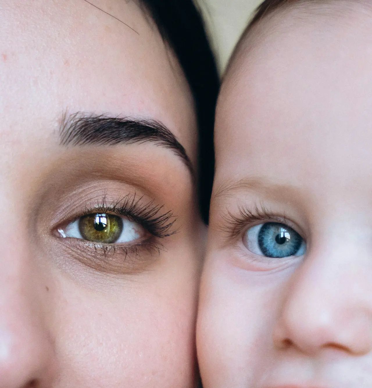 Close-up of a mother and baby, emphasizing contrasting green and blue eyes, fine details in eyelashes, and close bond.